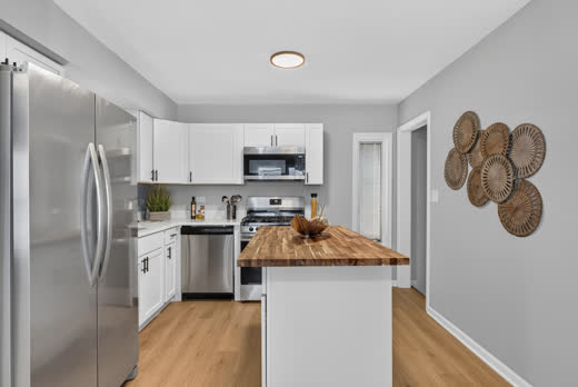 White shaker kitchen with stainless steel appliances and island at 9205 S Utica Ave