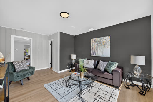 Staged living room with dark feature wall and open flow, 9205 S Utica Ave