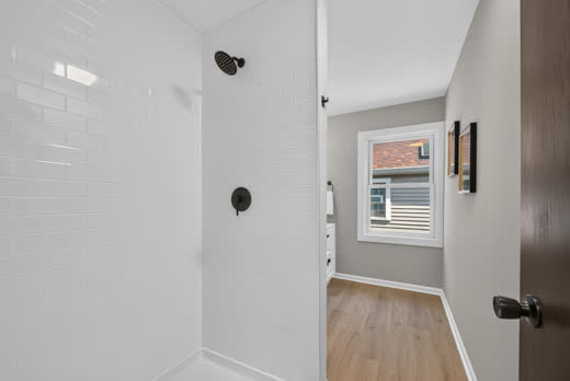 Renovated bathroom with white walk-in shower and matte black rain showerhead