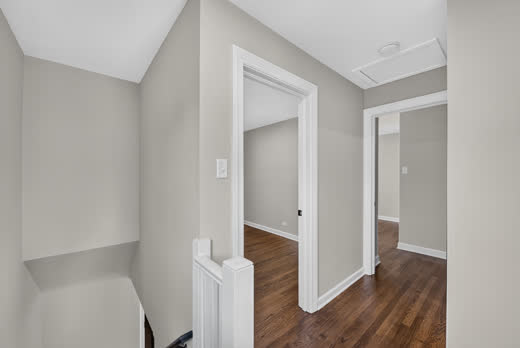 Upstairs hallway landing with refinished hardwood floors and white trim
