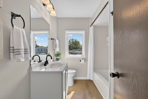Full bathroom with tub shower, white vanity, and black faucet at 9205 S Utica Ave