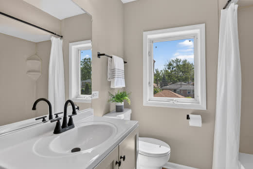 Remodeled bathroom with black gooseneck faucet and bright window views
