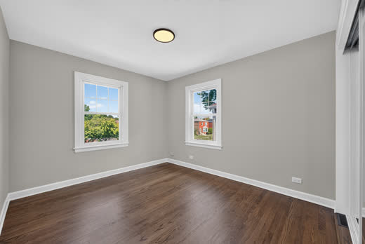 Spacious bedroom with two windows and dark hardwood floors, 9205 S Utica Ave