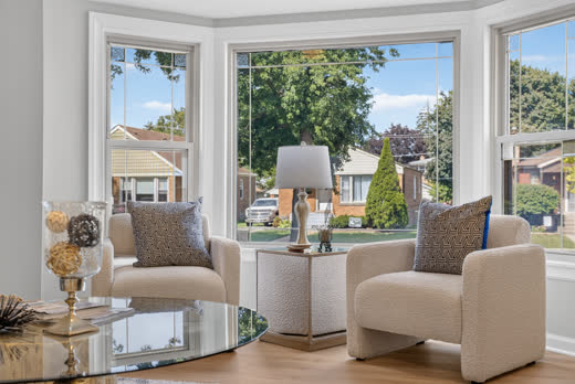 Bright bay window sitting area with boucle chairs in renovated Evergreen Park home