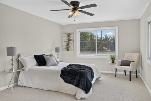 Spacious primary bedroom with ceiling fan and large window in Evergreen Park home