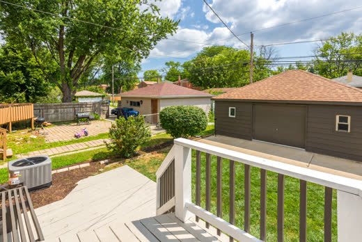 Backyard with paver patio and detached garage seen from deck at 9205 S Utica Ave