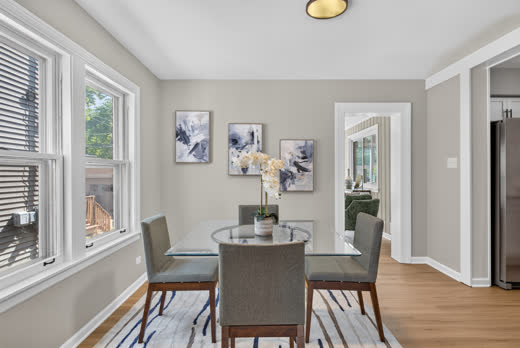Bright dining room with large windows and glass table in renovated Evergreen Park home